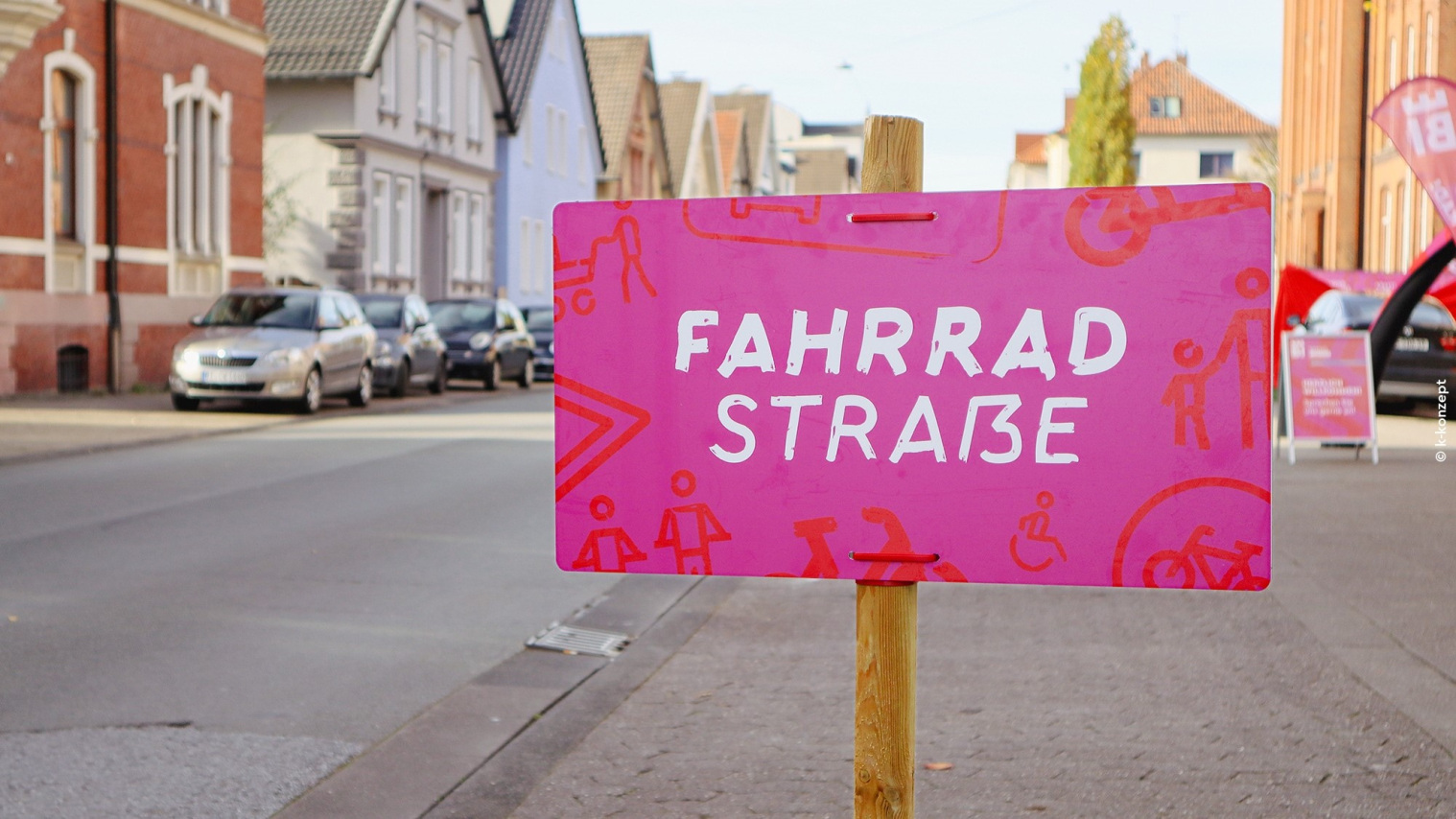 Ein Pinkes Schild steht an einer Straße. Auf dem Schild steht Fahrradstraße geschrieben.