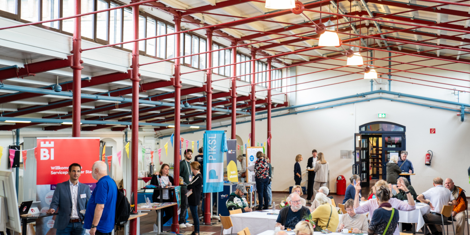 Ansicht auf die Stände und Tische beim Markt der digitalen Möglichkeiten 2024 im Historischen Saal der Volkshochschule.