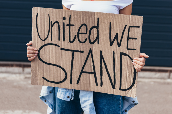 Frau hält ein Schild auf dem steht "united we stand"