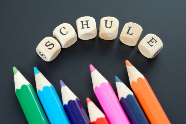 Stifte mit dem Schriftzug Schule darüber auf kleinen Holzwürfeln geschrieben