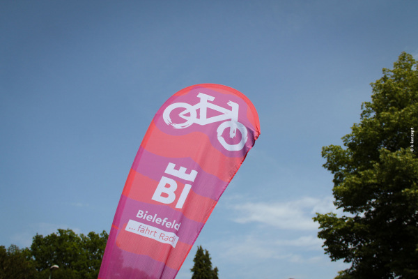 © k-konzept Beachflag mit der Aufschrift "Bielefeld fährt Rad" vor blauem Himmel
