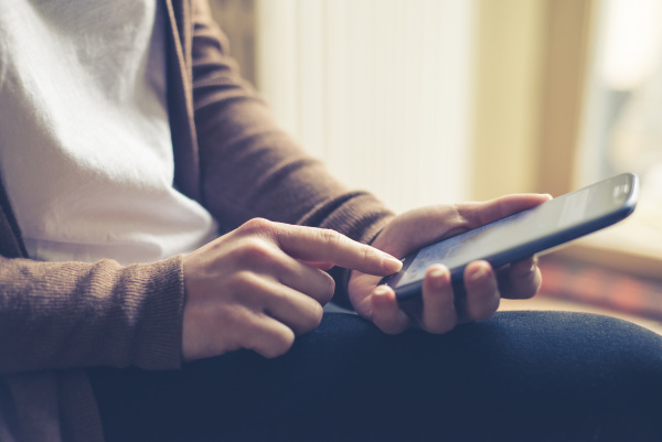 Eine Frau hält ein Handy und tippt auf den Bildschirm.