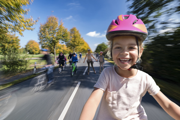 Ein fröhlich lachendes Kind auf dem Fahrrad, im Hintergrund weitere Radfahrende
