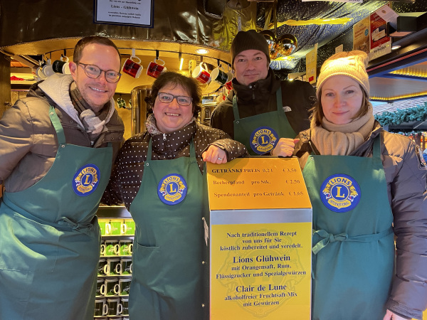 Vier Personen halten ein gelbes Plakat in der Hand.