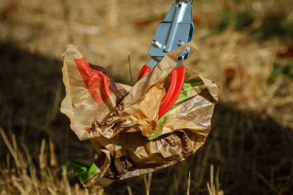 Mit einer Müllzange wird eine Papiertüte aufgehoben.
