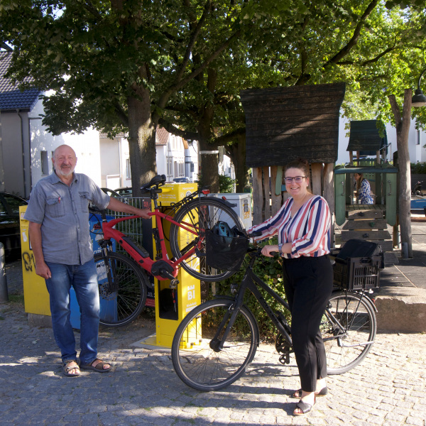 Ein Mann und eine Frau mit ihren Fahrrädern neben der neuen Radstation auf dem Siggi