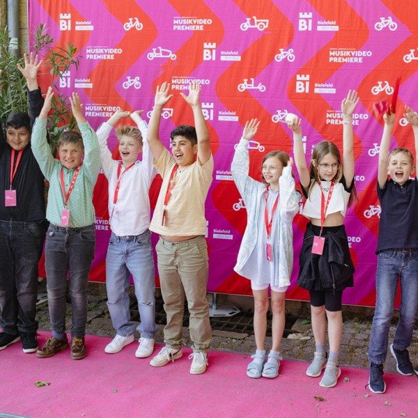 Kinder stehen in einer Reihe und halten die Hände nach oben