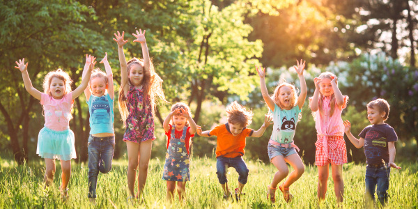 Kinder springen im Gras in die Luft