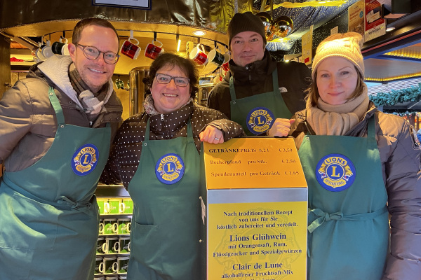 Vier Personen halten ein gelbes Plakat in der Hand.