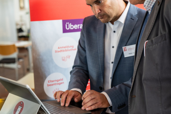 Am Stand des Serviceportals der Stadt Bielefeld schauen zwei Personen gemeinsam auf einen Laptop-Bildschirm.