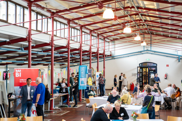 Ansicht auf die Stände und Tische beim Markt der digitalen Möglichkeiten 2024 im Historischen Saal der Volkshochschule.