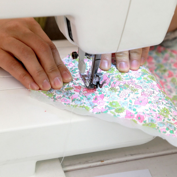 Hand näht Stoff an Nähmaschine