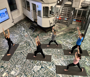 Fünf Frauen machen inmitten von Ausstellungsobjekten Yoga.